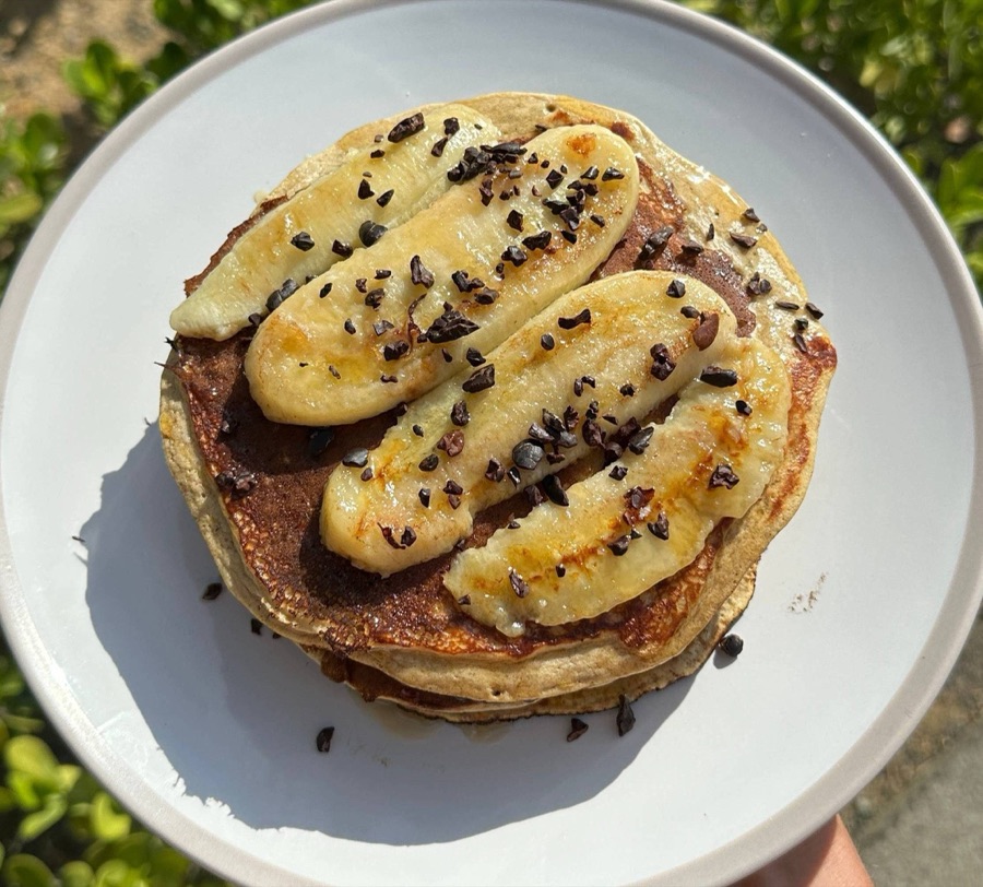 Stack of pancakes topped with caramelised banana and cacao nibs